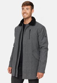 Abrigo de mezcla de lana gris con un cuello de piel sintética negra, bolsillo en el pecho con cremallera y bolsillos laterales. Tela texturizada con un corte entallado.