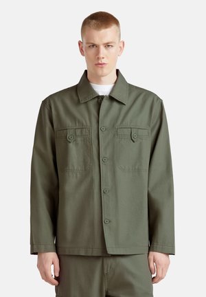 Olijfgroene jacket met een knoopsluiting aan de voorkant, twee borstzakken en een kraag. Gemaakt van duurzaam materiaal, met een ontspannen pasvorm en een rechte zoom.