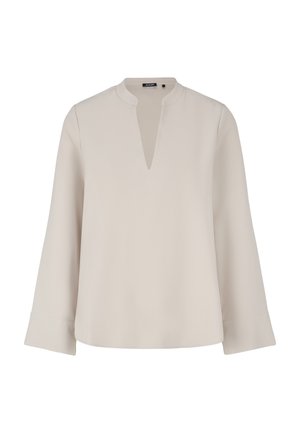 Blouse beige à manches longues avec un col rond ouvert et une fente en forme de V à l'avant, montrant un design simple et élégant.