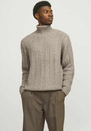 Grauer, gerippter Rollkragenpullover aus strukturiertem Strickmaterial, kombiniert mit locker sitzenden olivgrünen Hosen.