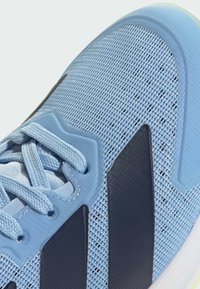 Light blue athletic sneaker featuring a mesh upper, tonal laces, and three black stripes on the side; rubber outsole for traction.