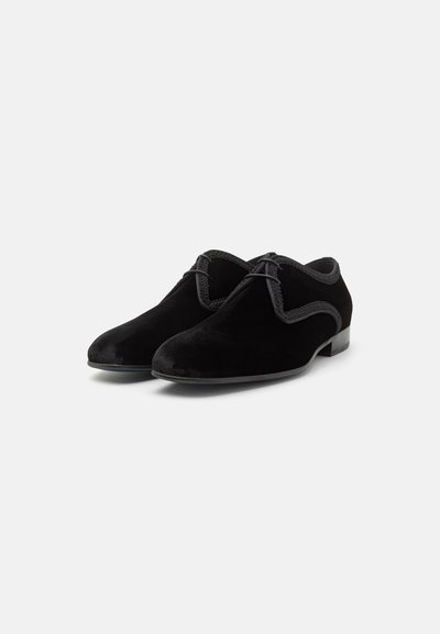 Chaussures derby en daim noir avec un design à lacets, des bords arrondis et un petit talon. Présente une couture discrète le long du bord supérieur pour plus de détails.