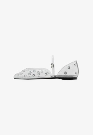 Transparent flat shoe with round cutouts, a small back strap, and a black sole. Features a smooth texture and minimalist design.