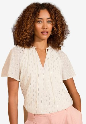 White blouse with short, slightly puffed sleeves, featuring vertical silver stripes and a notch collar. Worn with light pink trousers.
