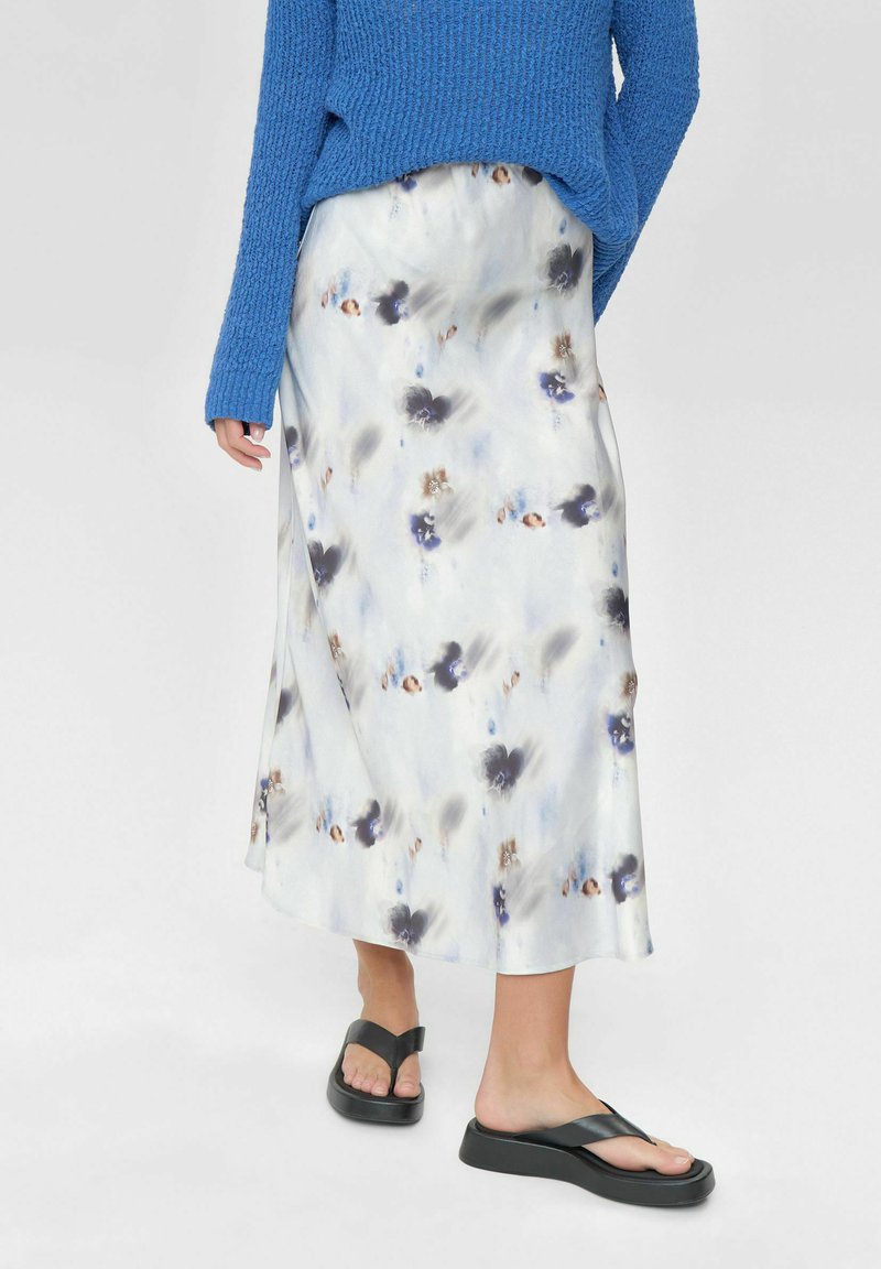 Hosszú, légies szoknya könnyű anyagból, fehér alapon kék és barna akvarell virágmintákkal. Kék kötött pulóverrel párosítva.