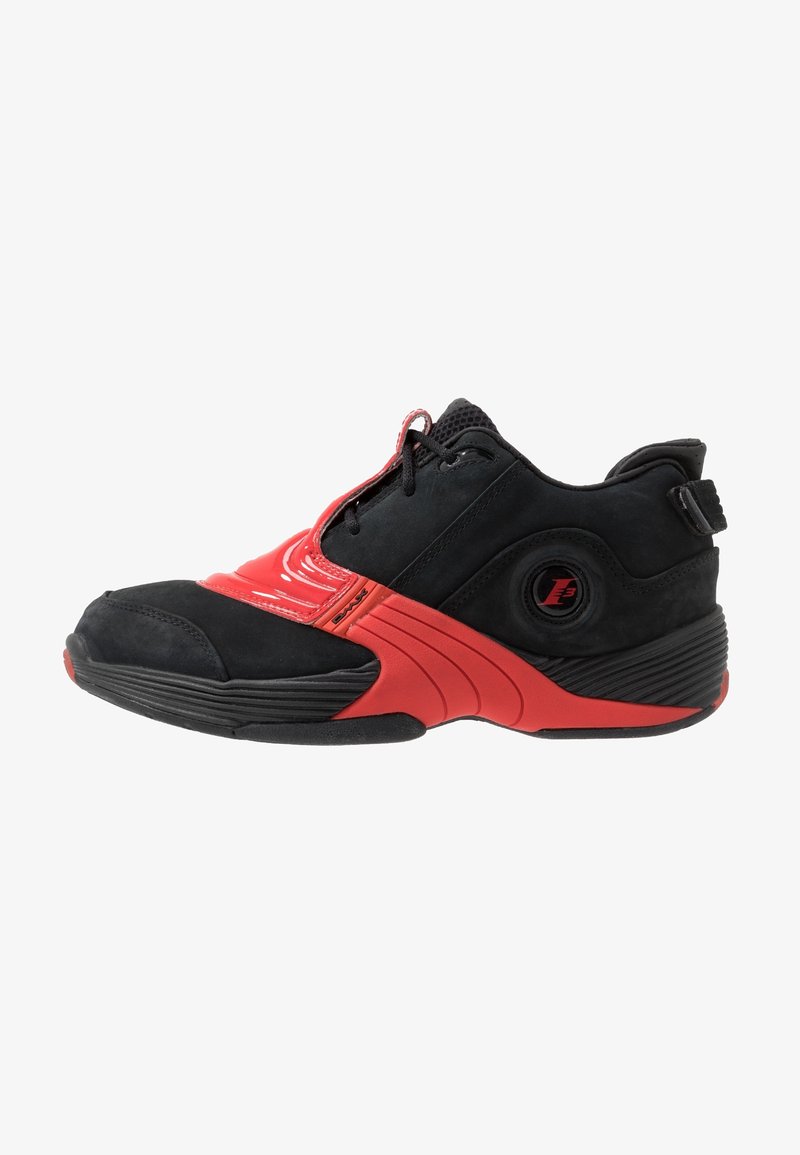 Baskets de sport noires et rouges avec profil bas, languette en mesh, lacets et semelle arrondie avec grip texturé.