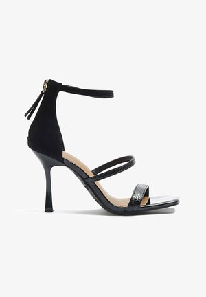 Czarne sandały na wysokim obcasie z teksturowanym zamszowym tyłem i błyszczącymi lakierowanymi paskami. Cienki pasek na kostkę z zapięciem na zamek.