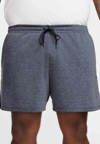 Pantalones cortos deportivos grises con cintura ajustable mediante cordón, bolsillos laterales y una tela suave y texturizada. Presenta un logo mínimo en negro en el lateral.