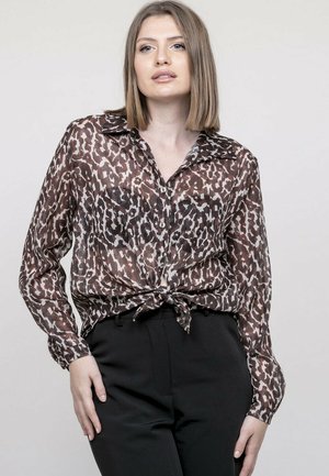 Blouse à imprimé léopard dans des tons de marron et de beige, avec des manches longues, un col, une fermeture à boutons sur le devant, et un détail de taille nouée.