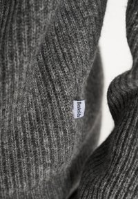 Grå ribbede sweater med en blød tekstur og lille logomærke, der fremviser et hyggeligt strikkemønster og varme stoffer.