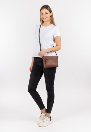 Borsa a tracolla in pelle marrone con una texture liscia, tasca con zip e tracolla regolabile. Forma rettangolare compatta, design minimalista.