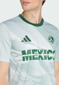 Bijela majica kratkih rukava s zelenim detaljima, s uzorkom, zelenim natpisom "MEXICO" i Adidas logom na prsima.