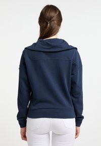 Marineblauwe hoodie met een brede kraag en lange mouwen. Zacht materiaal met een losse pasvorm, voorzien van een horizontale naad over de bovenrug.