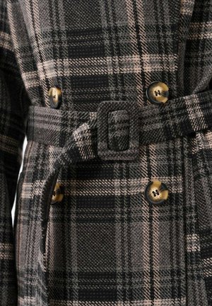 Plaid coat in black, gray, and pink tones with a belt, featuring gold buttons and a textured fabric. Square buckle accent at the waist.
