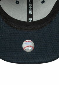 Schwarzer, texturierter Kragen eines Baseballtrikots mit New Era "39THIRTY"-Etikett und offizieller holografischer Echtheitsaufkleber der Major League Baseball.