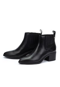 Par de botines de cuero negro con tacones de bloque, punteras afiladas y tiradores, con paneles laterales elásticos para un ajuste fácil de poner.
