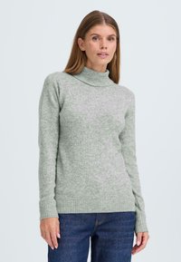 Hellgrüner Rollkragenpullover aus weichem Strickmaterial; mit langen Ärmeln und ribbelten Bündchen, in lässiger Passform.