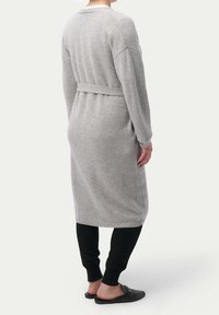 Grå lång cardigan i mjukt stickat tyg, med en knytbälte, ribbade ärmslut och en avslappnad passform, som matchas med svarta leggings och slip-on skor.