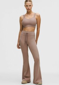 Brassière de sport marron clair côtelée et pantalon évasé assorti avec taille à cordon. Texture douce avec une coupe ajustée. Style minimaliste.