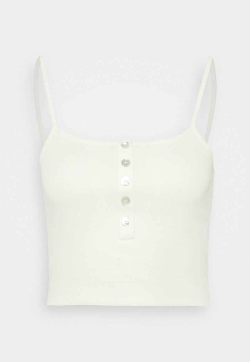 Débardeur court blanc avec fines bretelles et cinq petits boutons blancs sur le devant au centre.