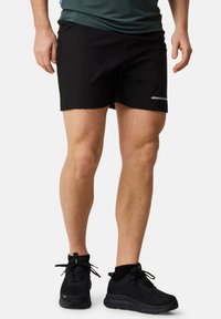 Svarta atletiska shorts med en smäcker design, sidofickor och reflekterande detaljer, tillsammans med svarta texturerade atletiska skor.