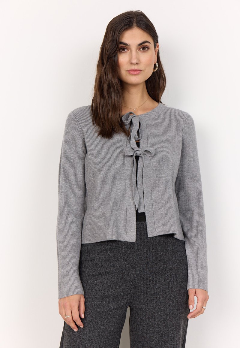 Grau gerippter Cardigan mit rundem Halsausschnitt und vorderem Bindebandverschluss. Lange Ärmel und cropped Design, kombiniert mit strukturierten grauen Hosen.