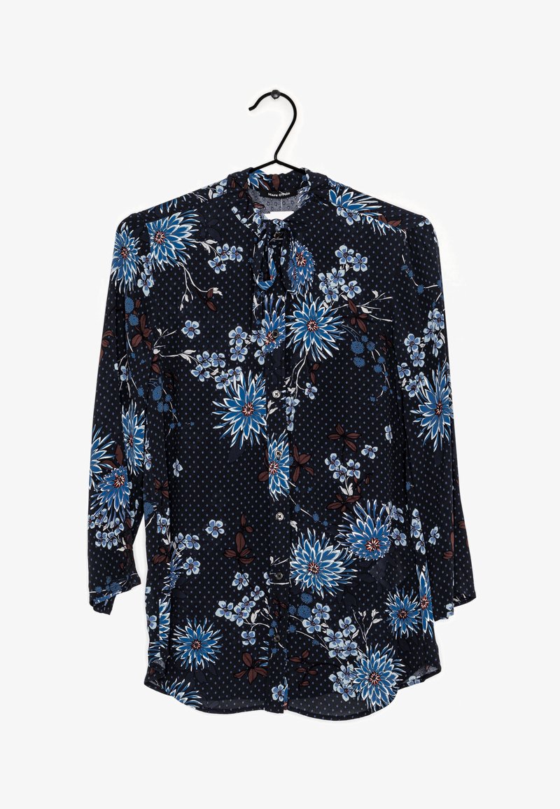 Blouse à manches longues navy en tissu léger ornée de grands motifs floraux bleu et marron, avec un col à nouer et une fermeture à boutons.