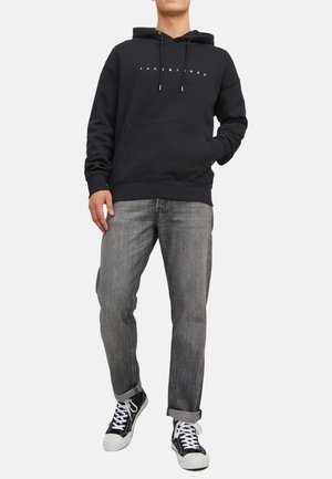 Hooded sweatshirt in black cotton with a front pocket, featuring a white logo. Paired with grey denim jeans and black sneakers.