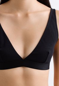 Zwarte bralette met een diepe v-halslijn, gemaakt van een gladde stof met een zachte textuur, en een brede onderband voor ondersteuning.
