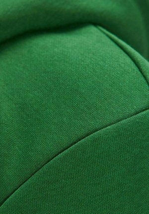 Dik groen stof met een soepele textuur, voorzien van een naaddetail en subtiele variaties in het weefpatroon over het oppervlak.