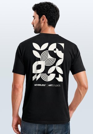Mann von hinten, trägt ein schwarzes T-Shirt mit auffälligen weißen abstrakten geometrischen Formen und dem Schriftzug „NEVERLESS ART STUDIOS“ auf dem Rücken.