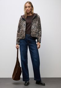 Faux furjacka med leopardmönster, mörkbrun topp, vida blå jeans och en mörkbrun axelväska. Svarta ankelstövlar.