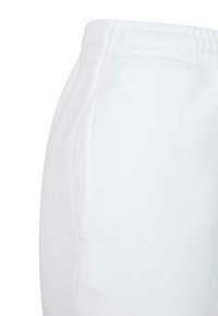 Witte joggingbroek met een elastische tailleband, zijzakken en een gladde textuur. De stof lijkt zacht en lichtgewicht.