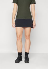 Falda deportiva negra combinada con una camiseta verde oscura. El conjunto presenta un diseño ajustado y está hecho de un tejido suave y transpirable.