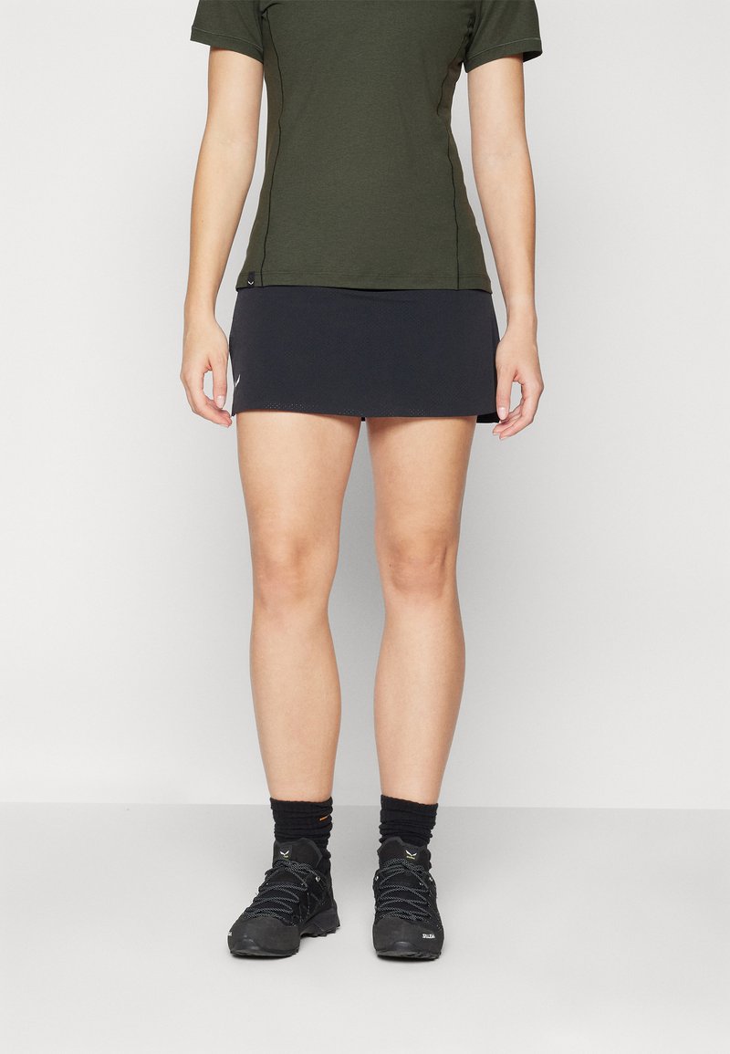 Falda deportiva negra combinada con una camiseta verde oscura. El conjunto presenta un diseño ajustado y está hecho de un tejido suave y transpirable.