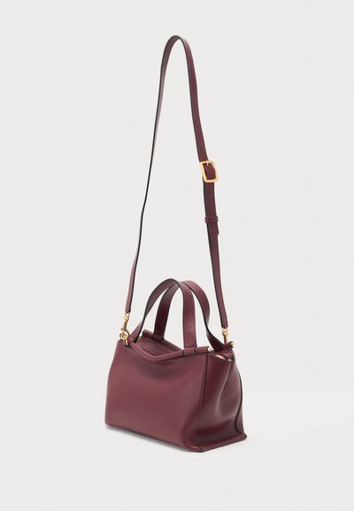 Petit sac à main en cuir bordeaux avec deux petites poignées et une longue bandoulière réglable avec une boucle dorée et des attaches dorées.