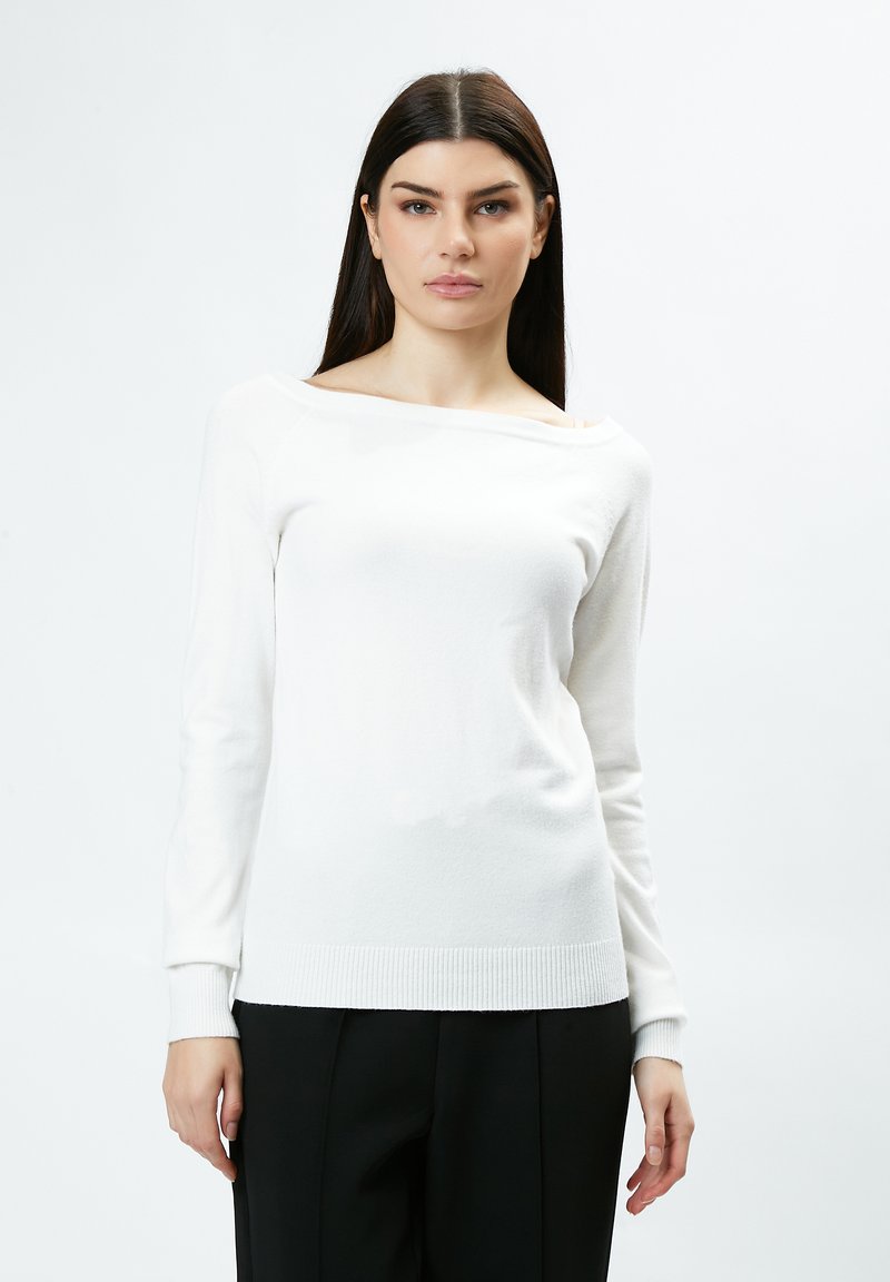 Pull blanc à manches longues avec un design décolleté et des poignets côtelés. Texture douce, silhouette ajustée et style minimaliste.