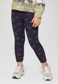 Leggings navy avec motif de cheval rouge, en mélange de coton, design ajusté et longueur cheville, assortis à des chaussures de sport multicolores.