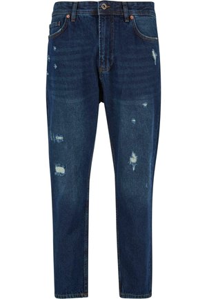 Dark blue denim jeans with a relaxed fit, featuring distressed patches and light fading, standard five-pocket design with copper hardware.