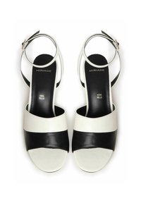 Sandalias de tacón alto de cuero en blanco y negro con punta abierta, correa en el tobillo y bandas horizontales en contraste. Textura suave destacable y marca.