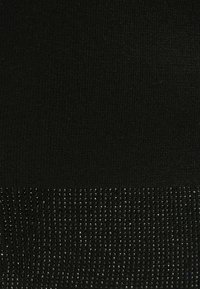 Čierna pletená látka s textúrovanou spodnou časťou a reflexnými detailmi pridáva vizuálny záujem a rozmer.