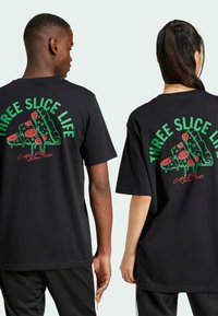 T-shirt nera in cotone con una grafica colorata di una pizza sul retro con la scritta "THREE SLICE LIFE" in verde. Maniche corte, vestibilità rilassata.