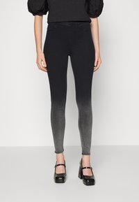 Leggings de denim negro con un degradado de gris oscuro a claro. Presentan una cintura alta, un ajuste ceñido en las piernas y dos bolsillos frontales.