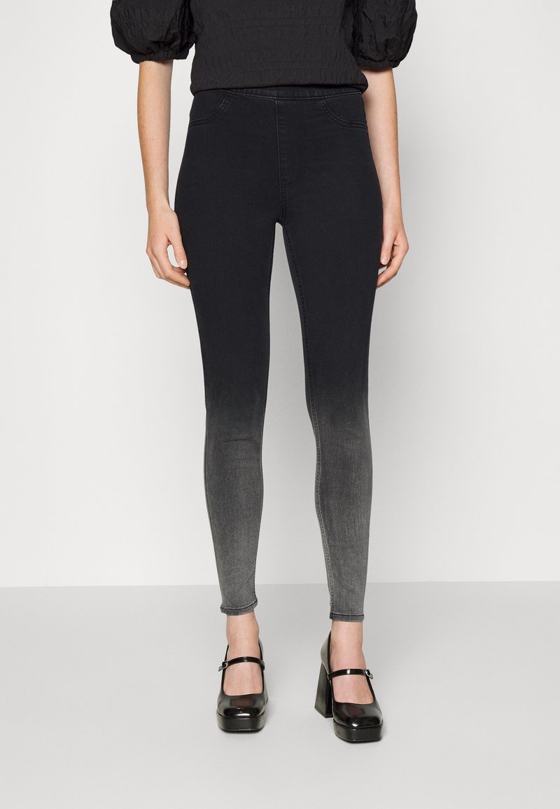 Leggings de denim negro con un degradado de gris oscuro a claro. Presentan una cintura alta, un ajuste ceñido en las piernas y dos bolsillos frontales.