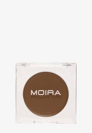 Kompakt gennemsigtig æske, der indeholder rundt brunt makeupprodukt med "MOIRA" trykt med hvide bogstaver på overfladen.
