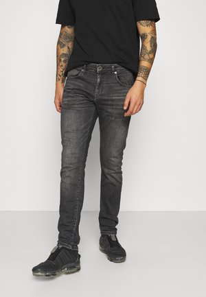 Slim-fit grijze jeans met een vervaagde afwerking, vijf-pocket ontwerp en een zwart shirt. Draag ze met gestructureerde zwarte sneakers met doorzichtige zolen.