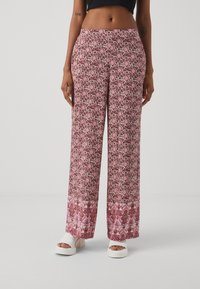 Pantaloni a gamba larga con stampa floreale nei colori rosa e bordeaux. Tessuto morbido con un orlo decorato. Abbinati a sandali platform bianchi.
