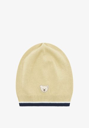 Berretto di lana giallo chiaro con una toppa a forma di orso sul davanti. Presenta un polsino a coste a righe blu navy e bianche. Texture morbida, forma arrotondata.