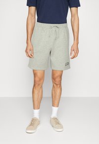 Shorts en mélange de coton gris avec taille à cordon, logo "GAP" brodé et poches latérales, associés à des baskets en daim beige et des chaussettes blanches.