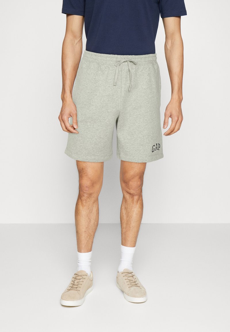 Graue Baumwollmischung-Shorts mit Kordelzugbund, gesticktem "GAP"-Logo und Seitentaschen, kombiniert mit beigen Wildledersneakern und weißen Socken.